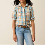 10079458 Ariat Girls Creekside Snap Shirt at boltranchstore.com A young woman modeling a light blue, peach, and white plaid western-style flannel shirt with rolled-up sleeves kids western shirt