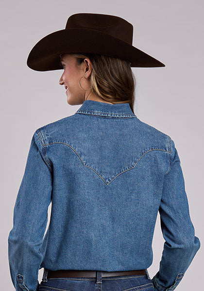 Woman wearing a blue denim shirt and brown cowboy hat 