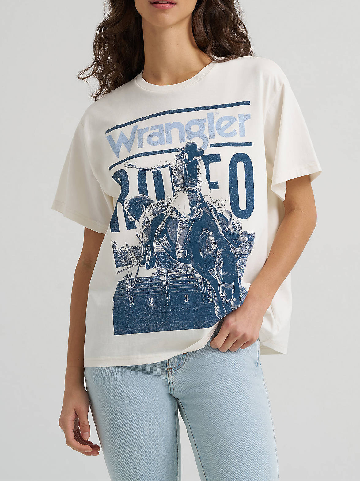 112379646 Wrangler Womens Rodeo Archive Girlfriend Graphic Tee at boltranchstore.com A woman modeling a Wrangler short-sleeve graphic t-shirt in off-white with a blue print in stock free shipping