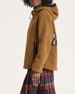 Woman wearing a brown fleece jacket with a patterned design on a white background
