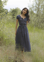 Woman in a blue dress standing in a grassy field with trees in the background doen dupe boltranchstore.com Bolt Ranch Store blue polka dot dress