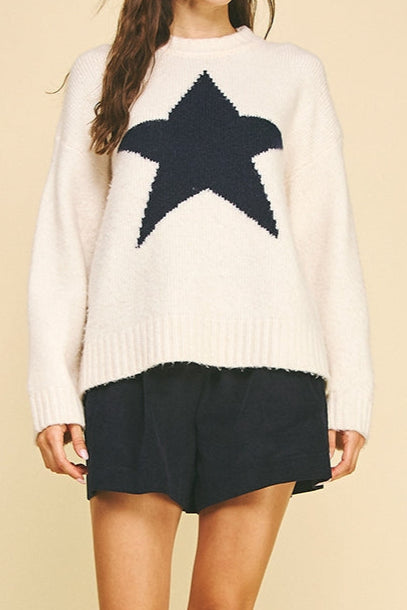 Woman wearing a white sweater with a navy star and black skirt on a beige background