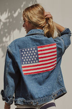 A denim jacket with an American flag patch on the back 