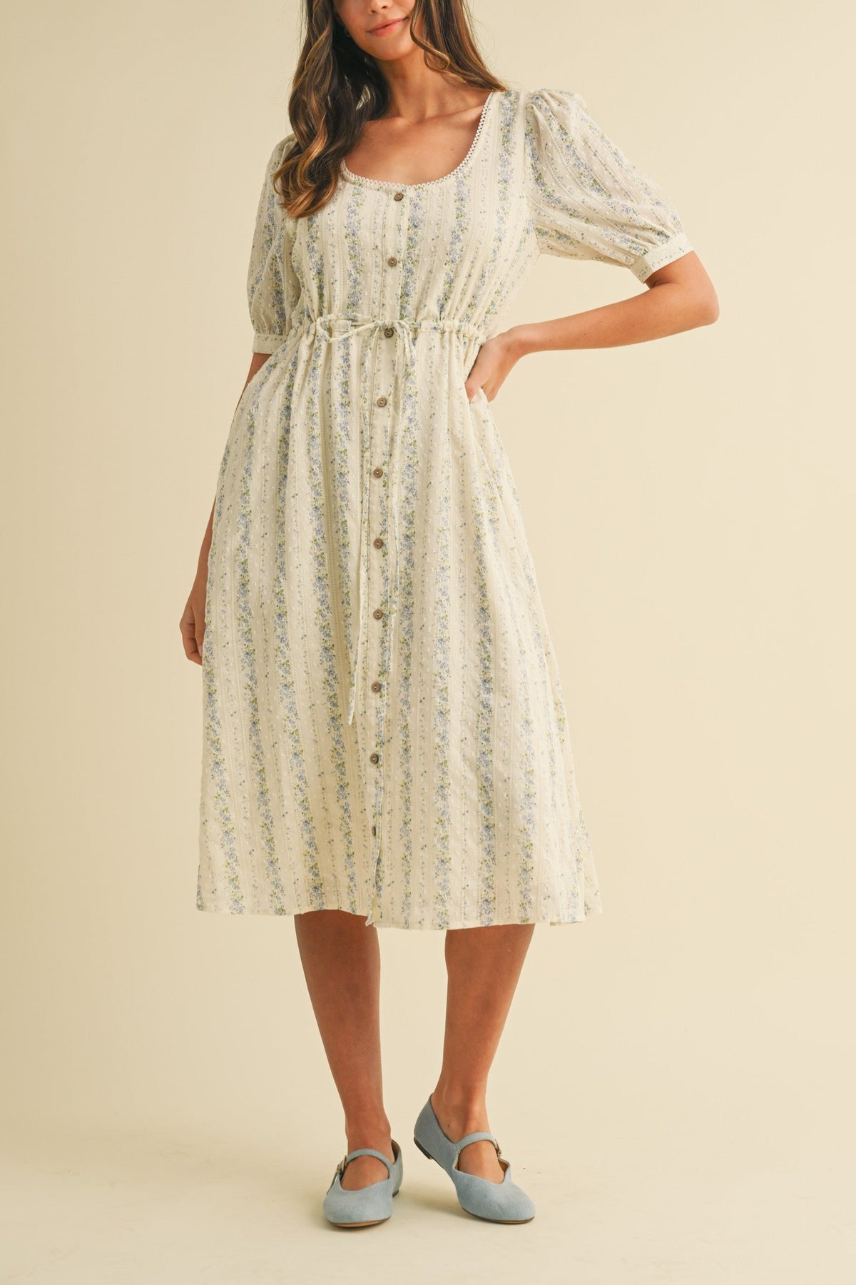 charming Andrea vintage floral midi dress features a delightful vintage floral print on textured Swiss dot fabric. It sports a scoop neckline, buttoned placket, and playful cupcake sleeves. With an elastic waist for a comfy fit, side pockets for convenience, and a fully lined design, this dress combines whimsy and comfort effortlessly. womens dress at Boltranchstore.com