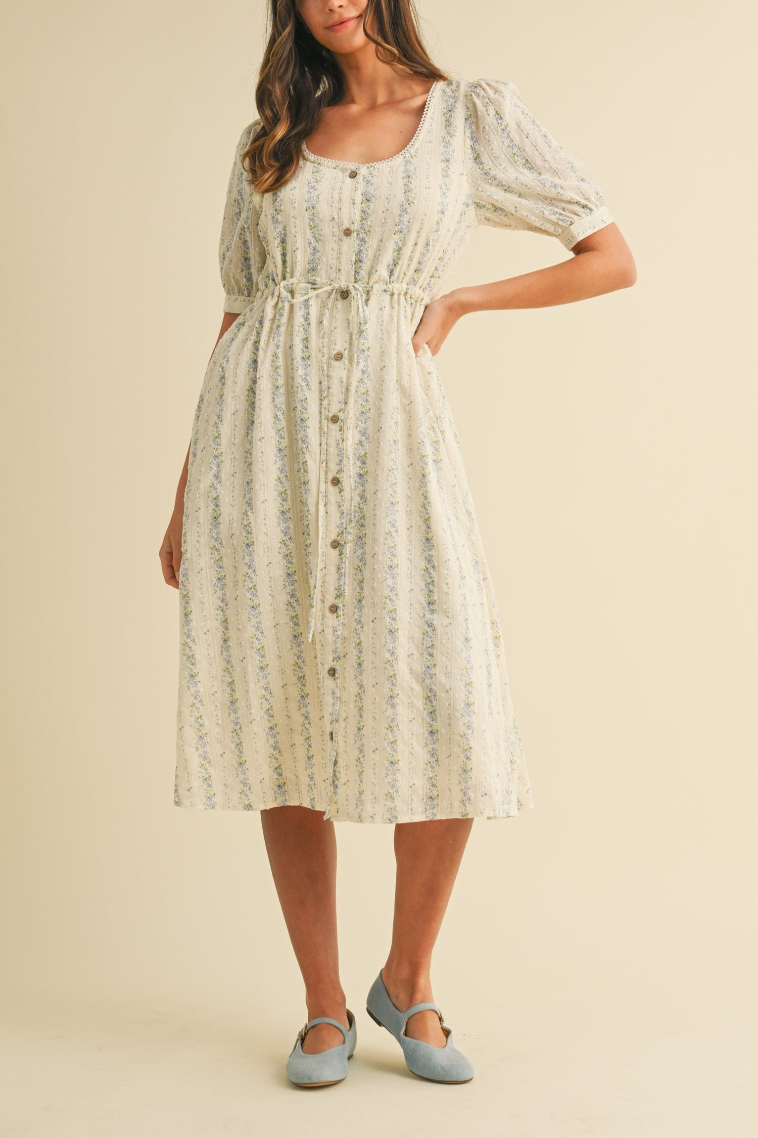 charming Andrea vintage floral midi dress features a delightful vintage floral print on textured Swiss dot fabric. It sports a scoop neckline, buttoned placket, and playful cupcake sleeves. With an elastic waist for a comfy fit, side pockets for convenience, and a fully lined design, this dress combines whimsy and comfort effortlessly. womens dress at Boltranchstore.com