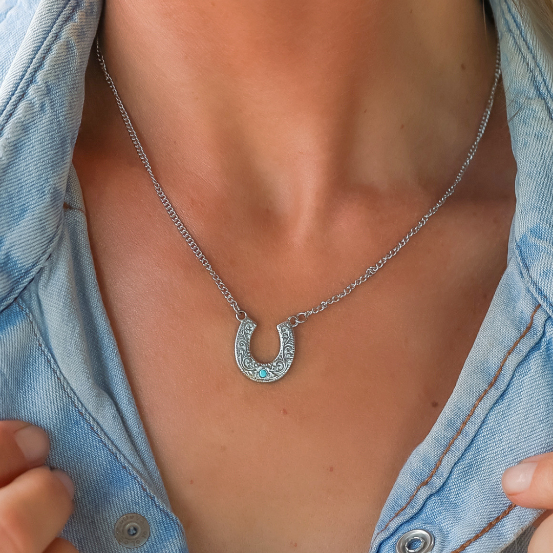 Antler Ring The Lucky Necklace at boltranchstore.com in stock free shipping A close-up of a person wearing a silver horseshoe pendant necklace with small light blue stones