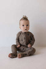 Bamboo Zip Pajamas Lightning Bolt shop at boltranchstrore.com Baby wearing a brown onesie with black patterns on a white background