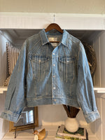 A light blue denim jacket with decorative silver-toned embroidery on the chest
