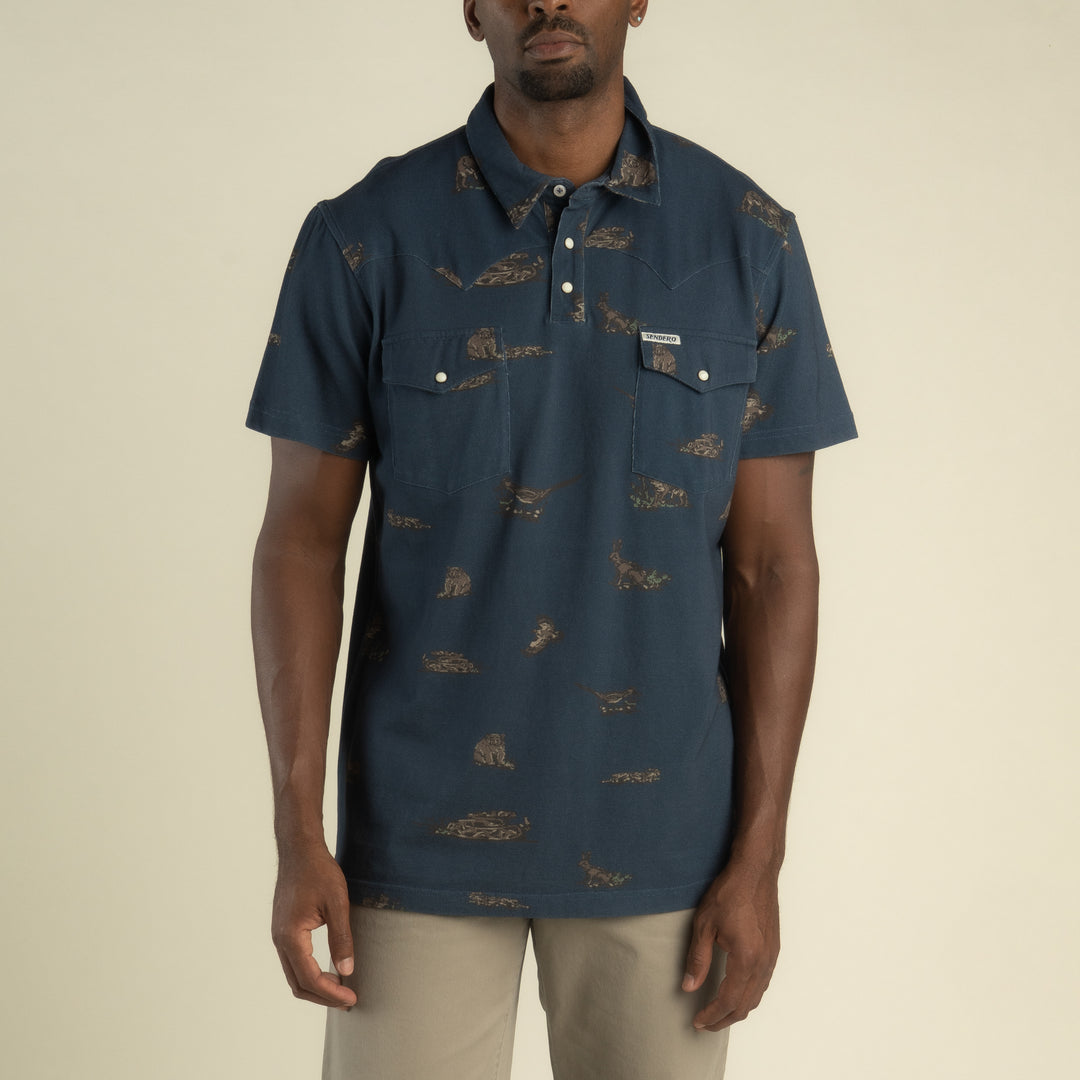 Cantina Pique Polo Short Sleeve Shirt At boltranchstore.com in stock free shipping A man wearing a dark blue short-sleeve button-up shirt with a brown animal print pattern.