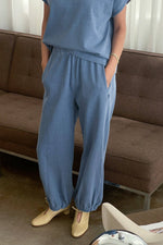 Person wearing blue pants and a matching top sitting on a brown couch. Cornflower Balloon Pants. Shop today at boltranchstore.com