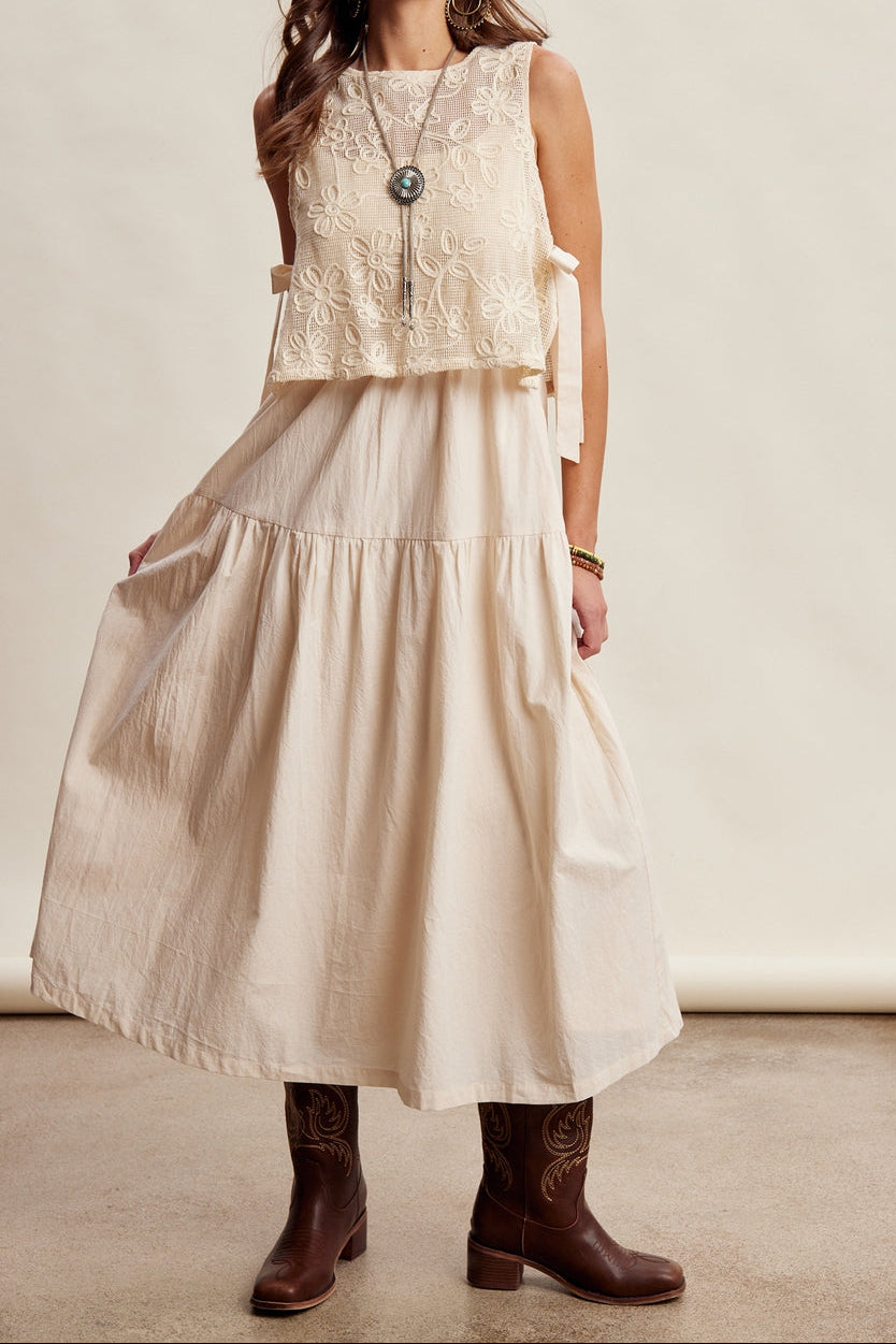 A beige sleeveless top with embroidered dress and tiered skirt with side ties and a round neck 