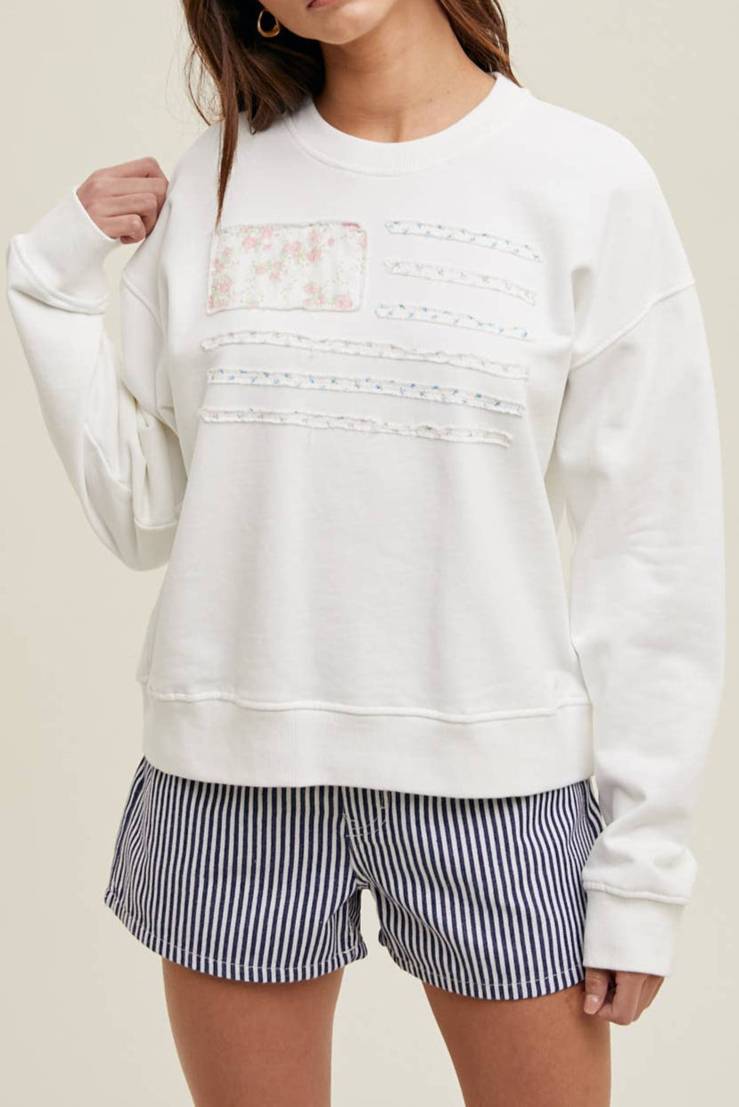Francine Floral Patch Flag Pullover wearing a white sweatshirt with lace detailing and striped shirt at boltranchstore.com