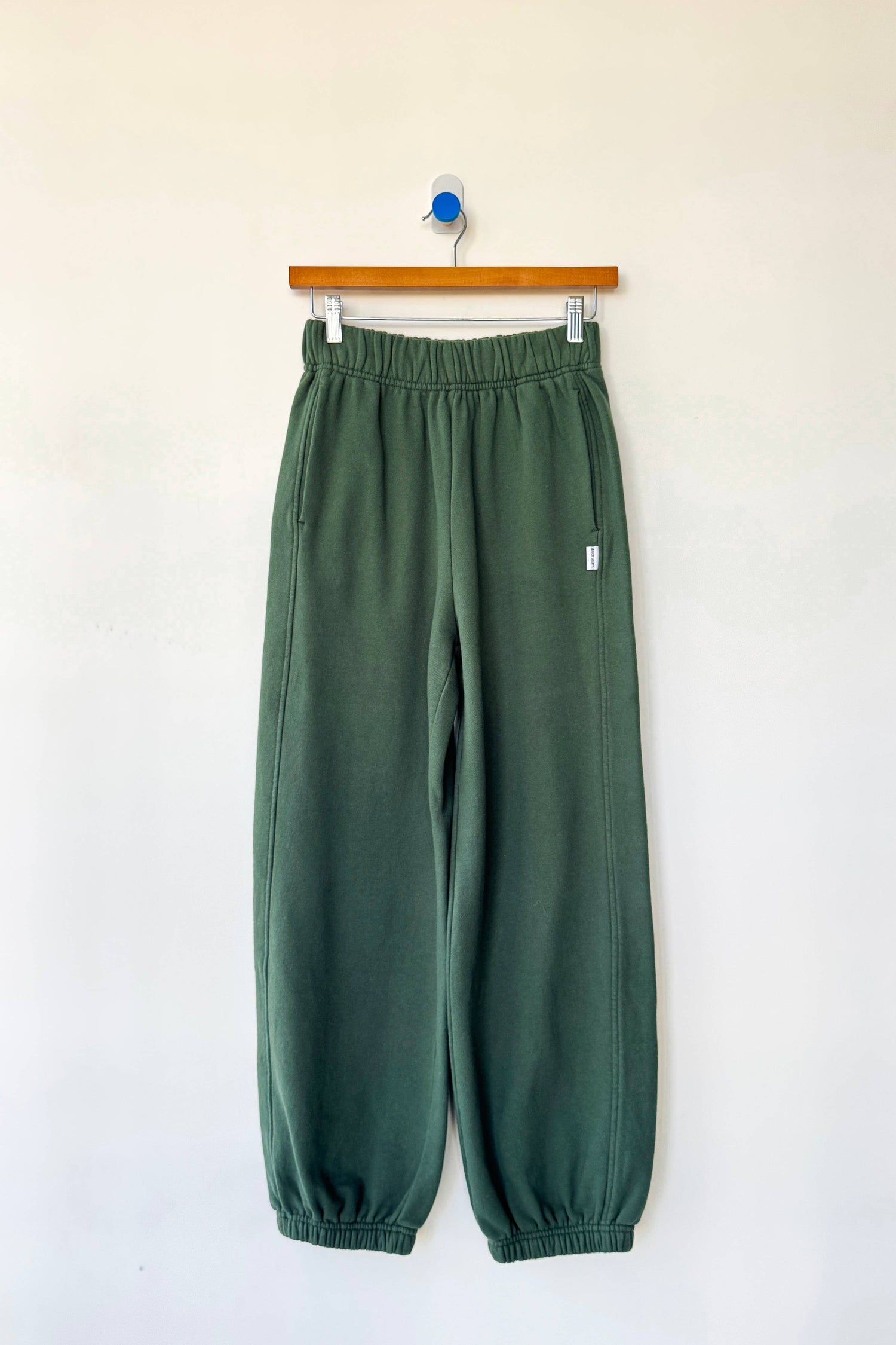 Green pants hanging on a wooden hanger against a white background French Terry Balloon Pants shop now at boltranchstore.com