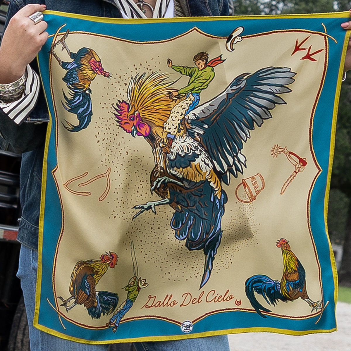 Fringe Scarves Gallo Del Cielo Silk Scarf Tan rooster of the sky with boot scootin cowboys on a tan ground with turquoise border womens western boutique Utah SKU SCRFGLCLTANSH25060