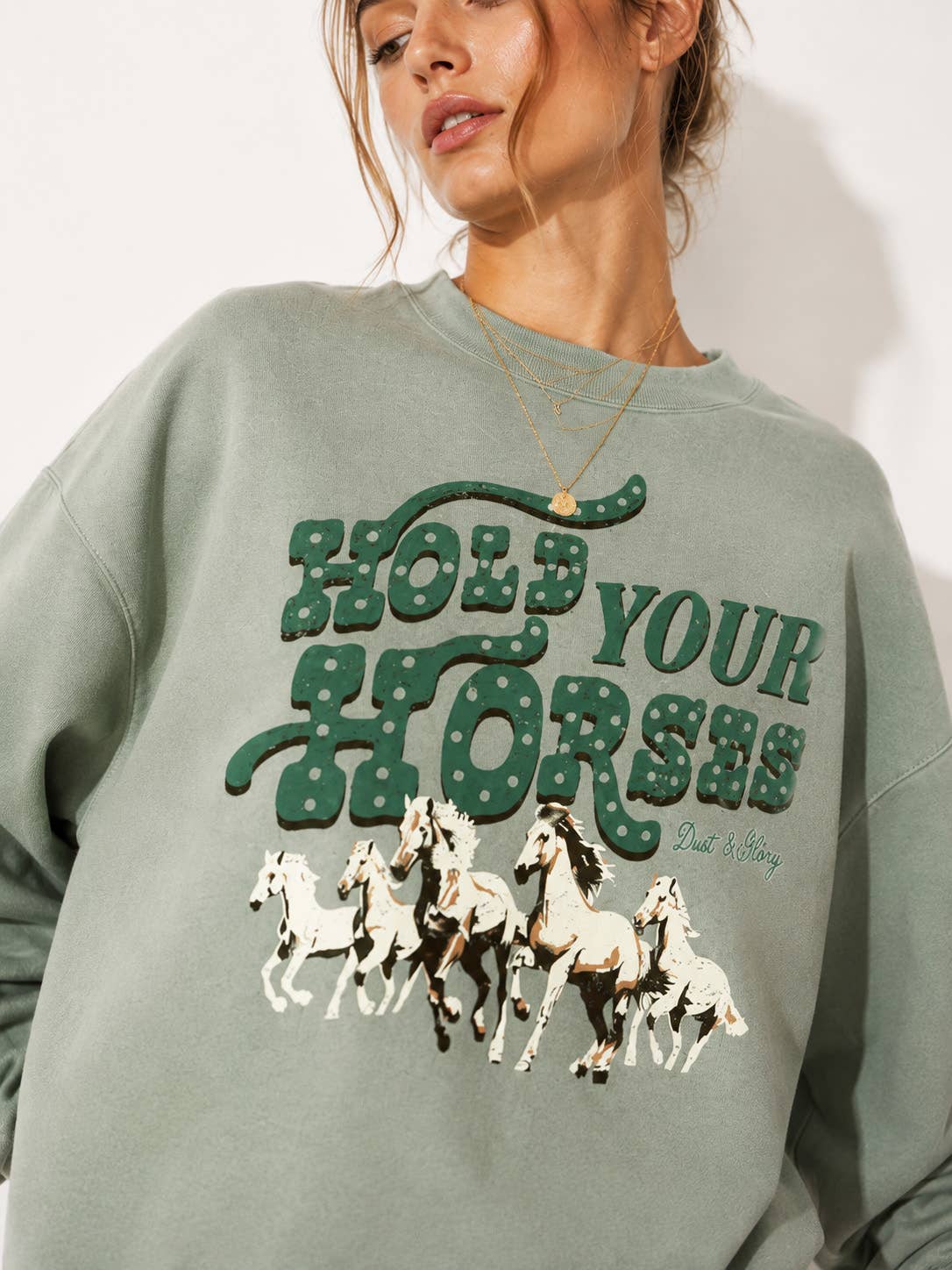 Hold Your Horses Western Sweatshirt sage green crewneck sweatshirt with a graphic that reads 'HOLD YOUR HORSES' in green and white, featuring an illustration of five white horses below. western wear bolt ranch store