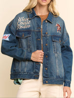  blue denim trucker jacket with 'West Coast Rodeo' embroidery, a horse patch, and a sleeve patch. LeAnne Western Trucker Jacket Blue denim black denim patch bomber jacket at bolt ranch store in Kamas Utah