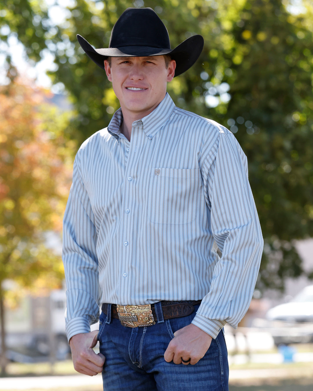 Cinch Mens Long Sleeve Stripe Shirt Light Blue worn with a trophy buckle and dark denim for rodeo and ranch days Park City