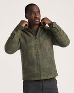 Pendleton Mens Quilted Chamois Work Jacket find at boltranchstore.com
A man wearing an olive green zip-up jacket with a tan allover scenic pattern, posing with his hands on the collar against a light gray background.