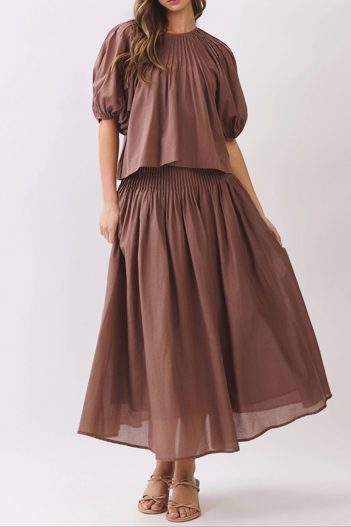 Pintuck Puff Sleeve Top at boltranchstore.com free shipping set in stock A woman wearing a brown two-piece set consisting of a short puff-sleeve top and a matching pleated maxi skirt