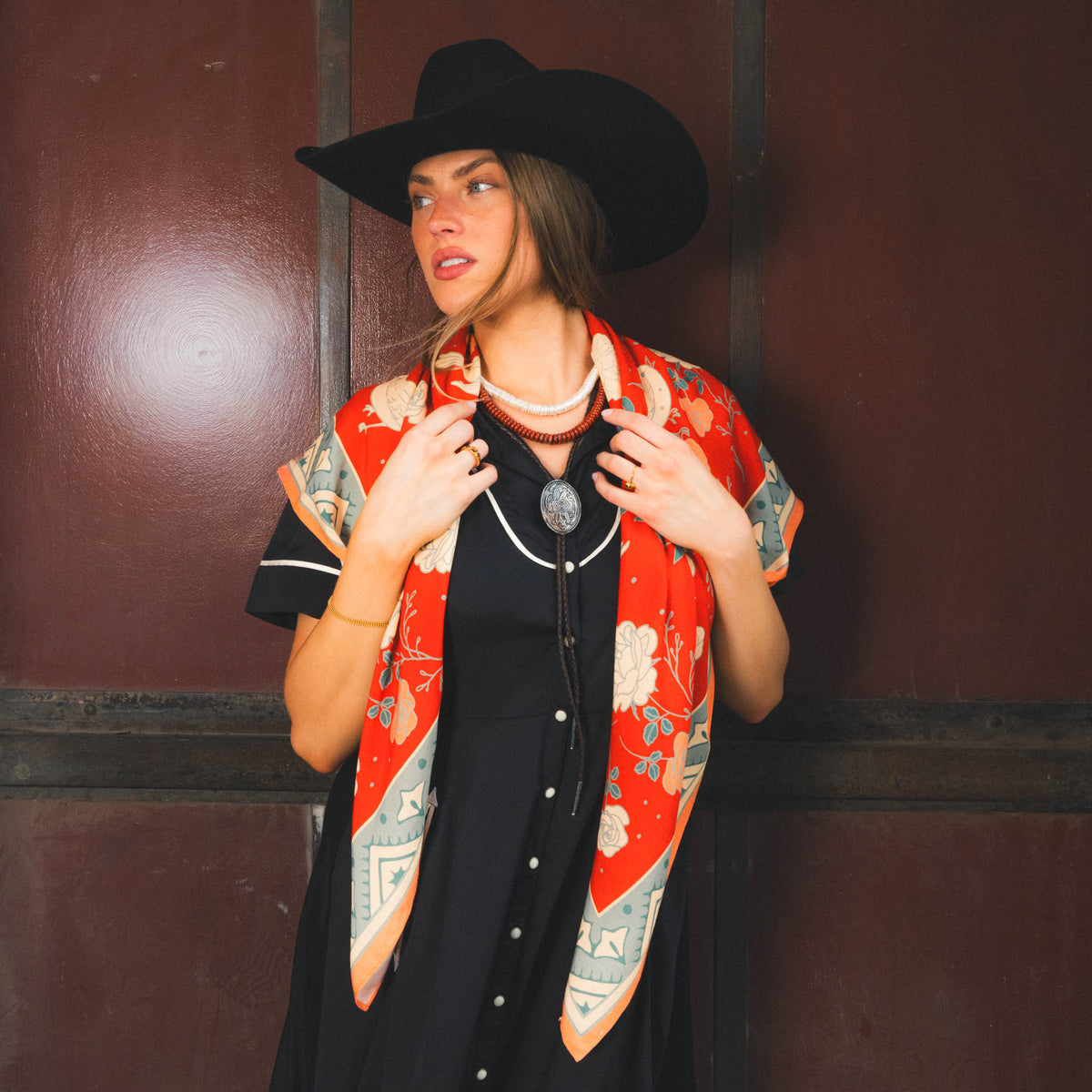 Sendero Rose Dove Bandana Scarf Red Teal draped over the shoulders as a lightweight shawl for rodeo nights