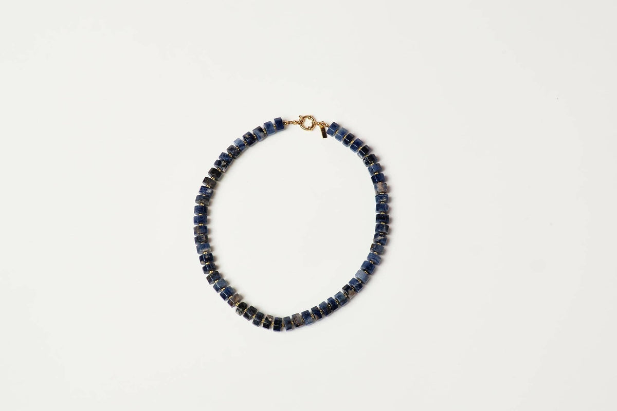 A beaded necklace made of small dark blue lapis lazuli stone beads with a gold clasp shop at boltranchstore.com