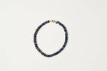 A beaded necklace made of small dark blue lapis lazuli stone beads with a gold clasp shop at boltranchstore.com