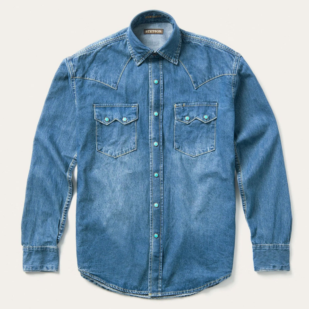 Stetson Blue denim shirt with turquoise button details, snap down pockets with two yokes, one yoke on each side of the shoulder in a medium wash long sleeve shirt.