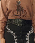 Stetson x THE GREAT Tooled Corset Belt Black worn over a graphic sweatshirt and embroidered skirt western fashion Kamas Utah