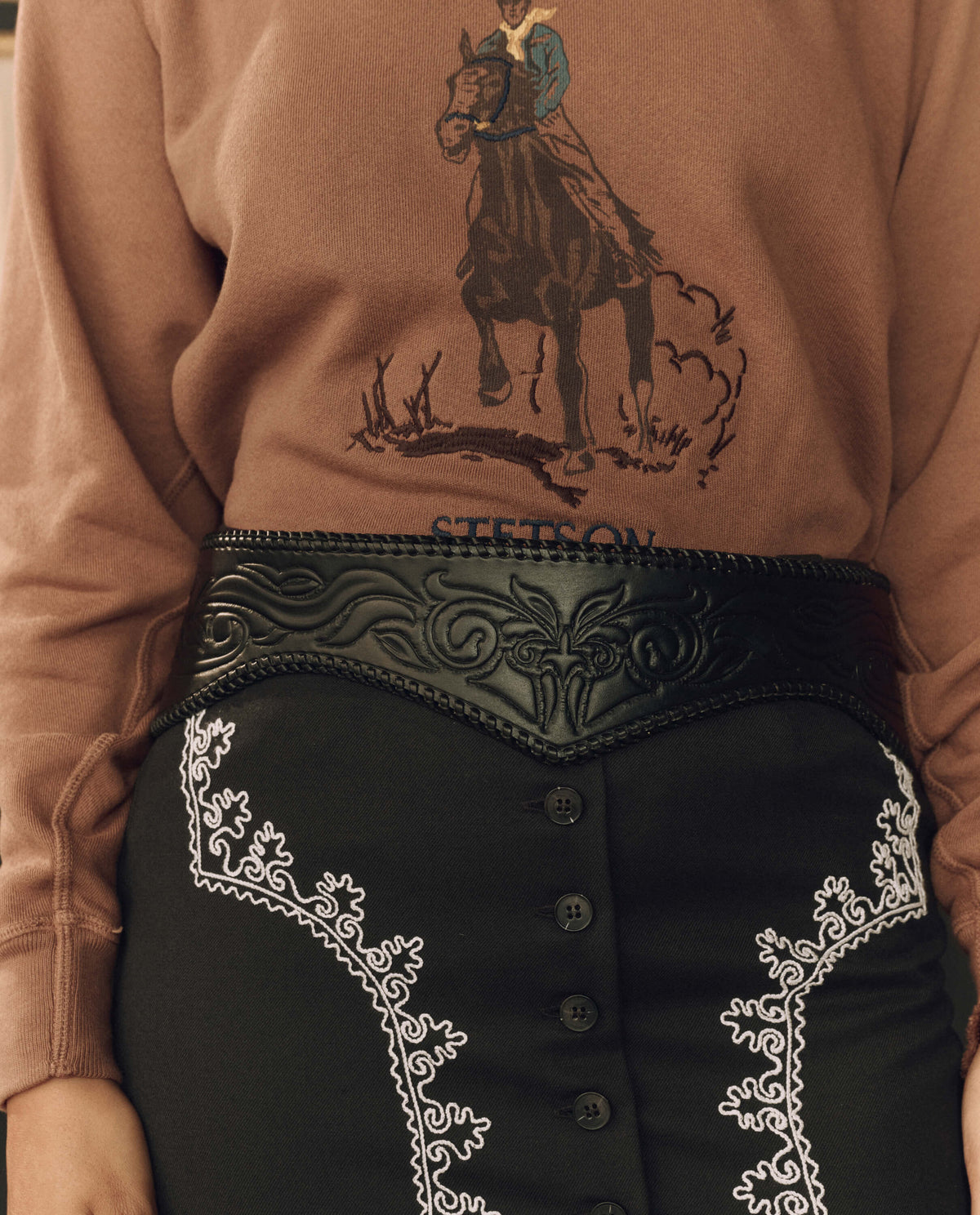 Stetson x THE GREAT Tooled Corset Belt Black worn over a graphic sweatshirt and embroidered skirt western fashion Kamas Utah