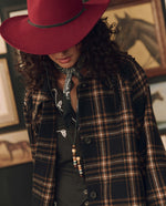 Stetson x THE GREAT Fringe Coat layered over a black skirt with a felt hat and boots cowgirl style