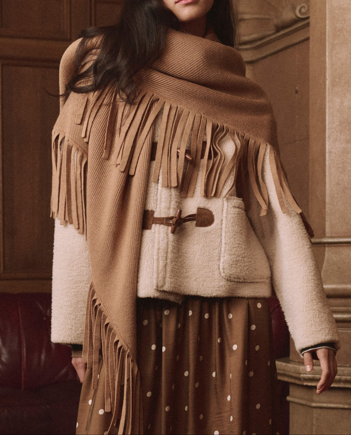 The Great Big Sweater Fringe Scarf Camel wrapped over a cream toggle coat for layered western fashion
