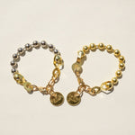 Twisted Silver Ball And Chain Bracelet at boltranchstore.com free shipping in stock Two beaded bracelets on a light beige background. One bracelet is metallic silver with gold-toned chain links and round charms, and the other is gold-toned with silver-toned chain links and round charms.