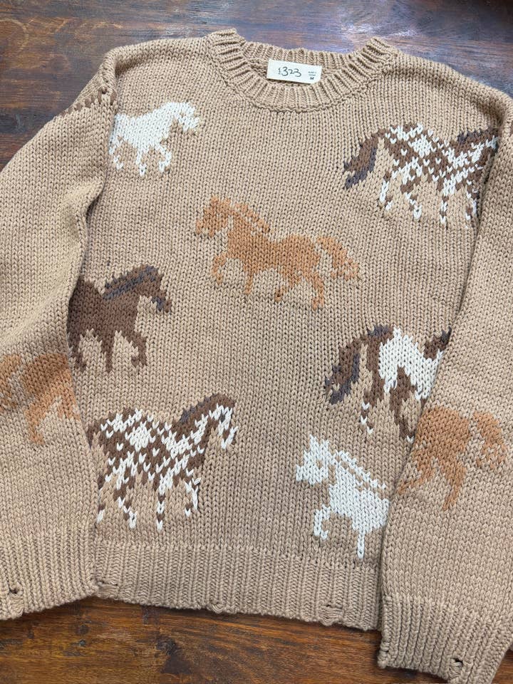 A beige knit sweater featuring a pattern of various horse illustrations in brown, tan, and white. 