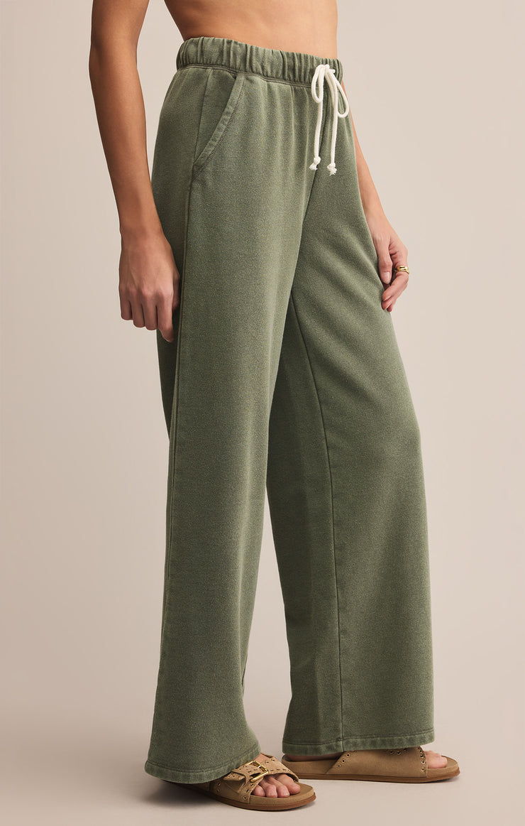 Person wearing green wide-leg pants with a beige background