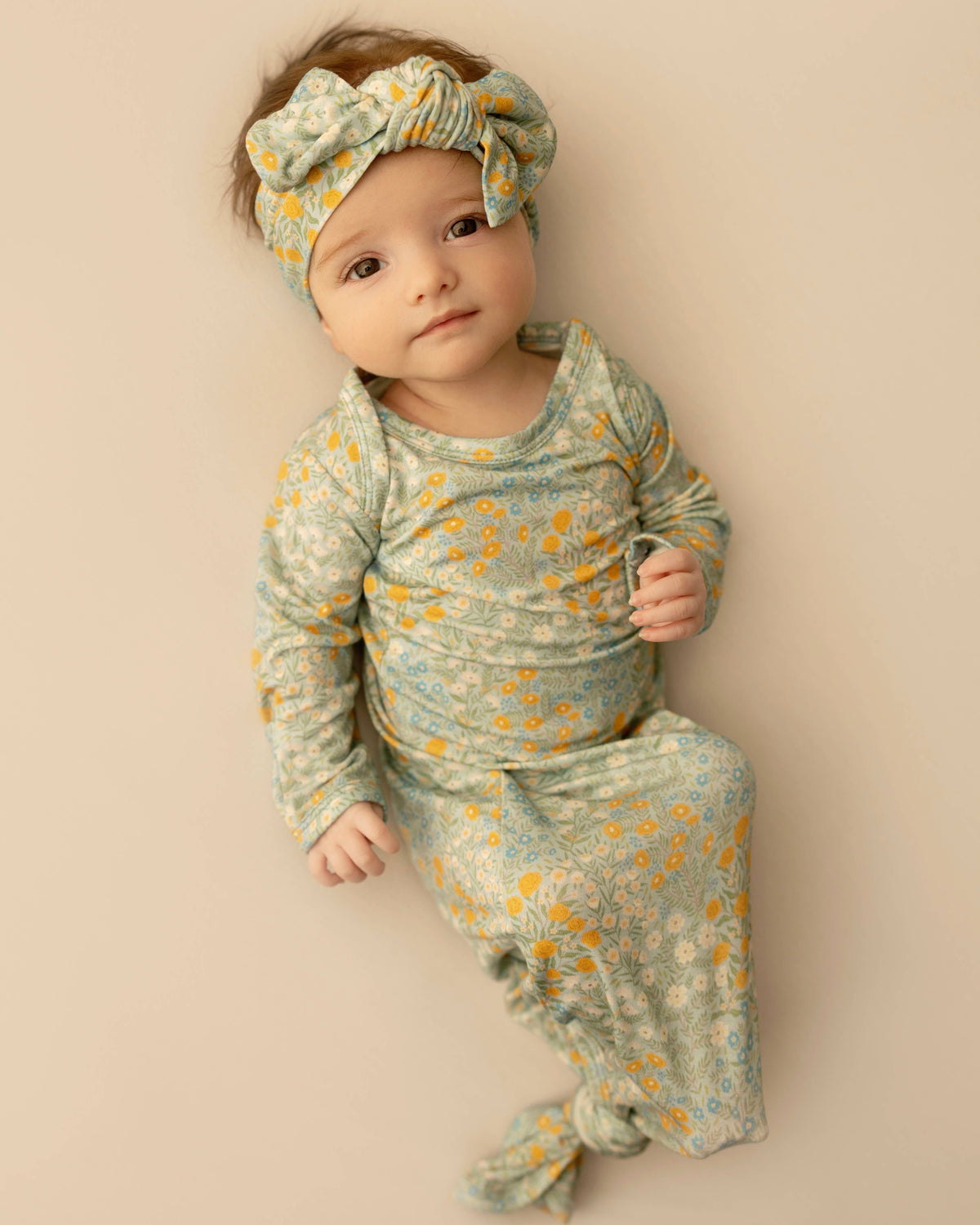 Baby in floral outfit and headband on a beige background Blue Meadows Knotted Infant Gown Shop today at boltranchstore.com 