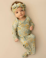 Baby in floral outfit and headband on a beige background Blue Meadows Knotted Infant Gown Shop today at boltranchstore.com 